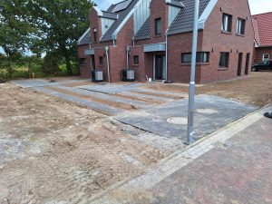 Neubau eines Mehrfamilienhauses mit neu angelegter Zufahrt in Form von Beton-Fahrstreifen, Pflasterfläche und zwei Revisionsdeckeln im Gehwegbereich.