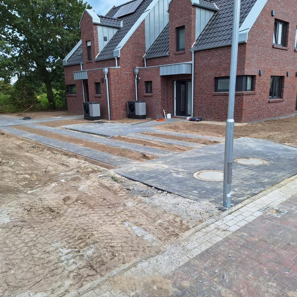 Neubau eines Mehrfamilienhauses mit neu angelegter Zufahrt in Form von Beton-Fahrstreifen, Pflasterfläche und zwei Revisionsdeckeln im Gehwegbereich.